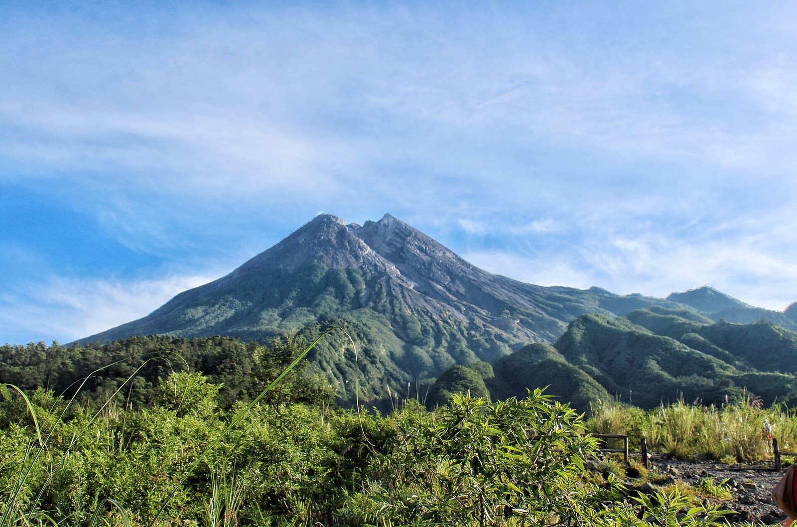 The summit cone of Mount Merapi above green lower slopes