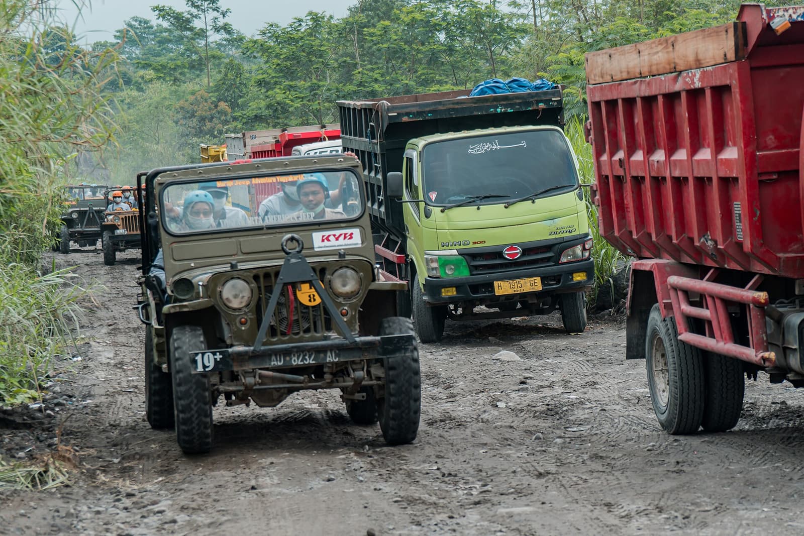 A tour jeep and sand trucks sharing a track on the slopes of Merapi