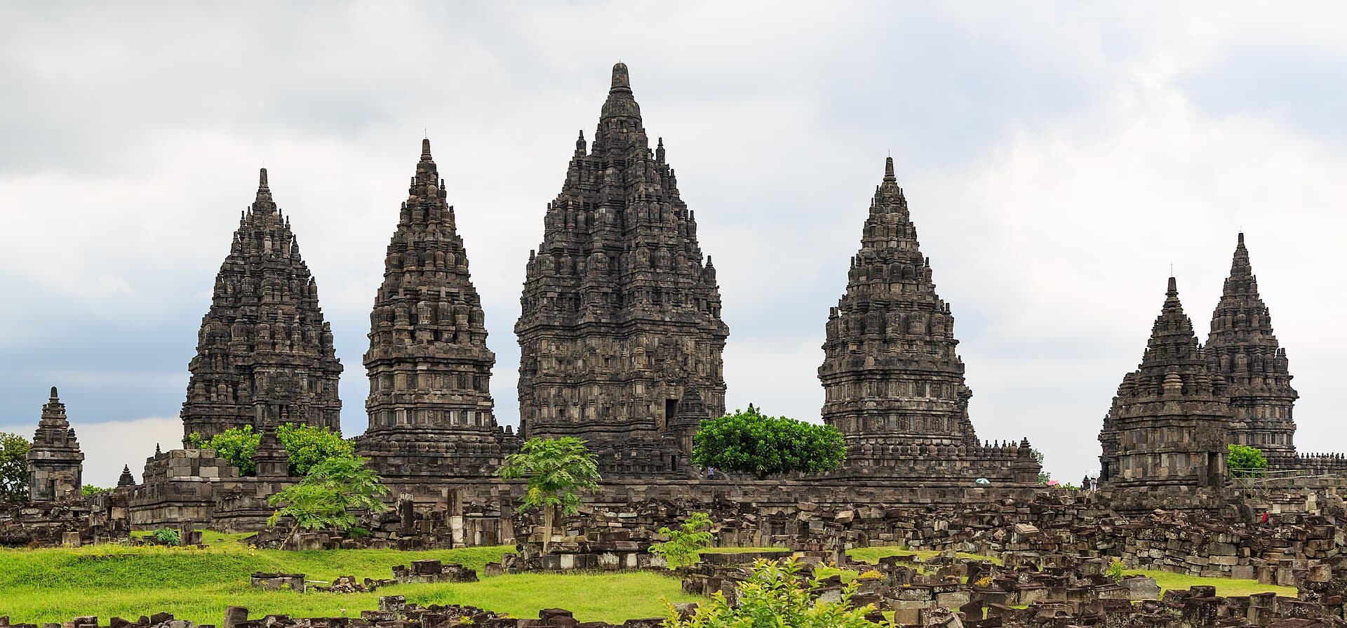 The row of tall temple towers at Prambanan above fallen stone blocks